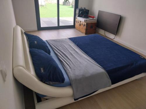 Cette chambre comprend un lit avec des draps bleus et une télévision. dans l'établissement Maison entière, à Guidel