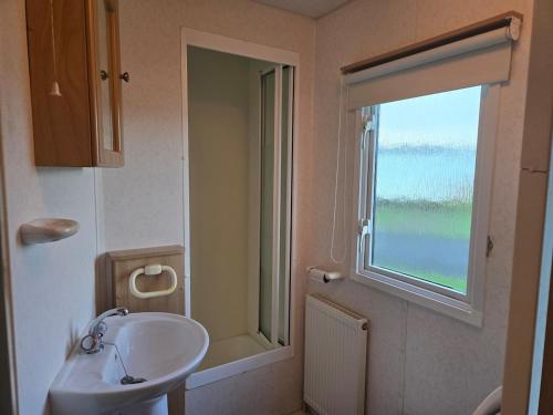 a bathroom with a sink and a window at Elf Wood Lodge - Swimming Spa, Sky Sports, Tennis, Hadrian's Wall listing in Port Carlisle