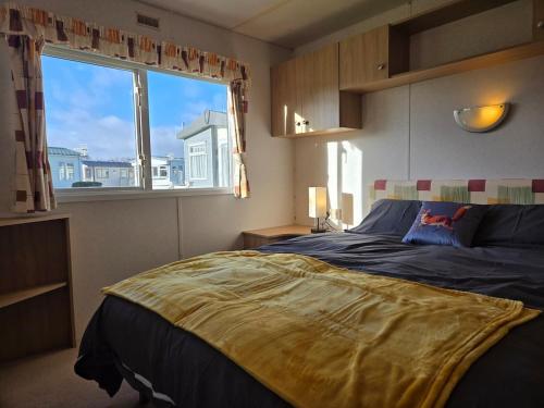 a bedroom with a large bed with a large window at Elf Wood Lodge - Swimming Spa, Sky Sports, Tennis, Hadrian's Wall listing in Port Carlisle