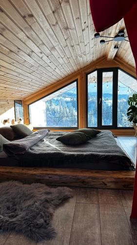 a large bed in a room with windows at Карпатське Hygge котедж для двох з чаном-джакузі у горах in Slavske