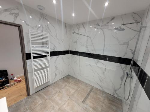 ein Bad mit einer Dusche mit schwarzem und weißem Marmor in der Unterkunft Villa Noyers, 1 heure de Paris à la campagne in Serbonnes