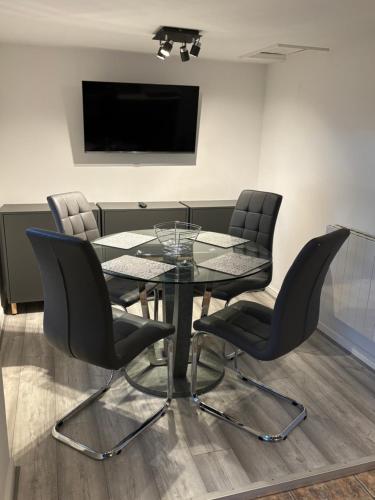 a dining room with a glass table and chairs at Sandhill House Mews in Troon