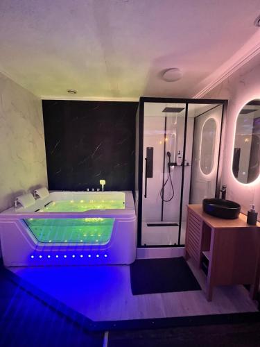 La salle de bains est pourvue d'une baignoire et d'une douche avec des lumières bleues. dans l'établissement Apartment Cinema, Jacuzzi, Borne arcade, à Bordeaux