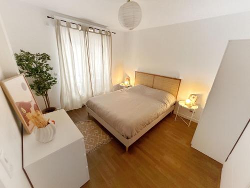 une chambre avec un lit et une plante en pot dans l'établissement Appartement cosy aux portes de Paris, à Levallois-Perret