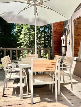 a table and chairs with an umbrella on a porch at Modern and Private Cabin in the Woods in Carnelian Bay