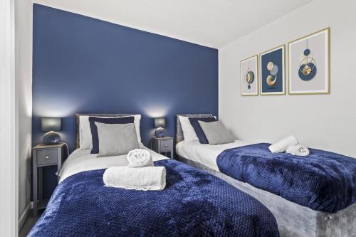 two beds in a room with blue walls at 2 Bedroom Serviced Apartment in Kettering Centre- Northampton, Sleeps 4, free parking, Wifi, Sky, Netflix in Northampton