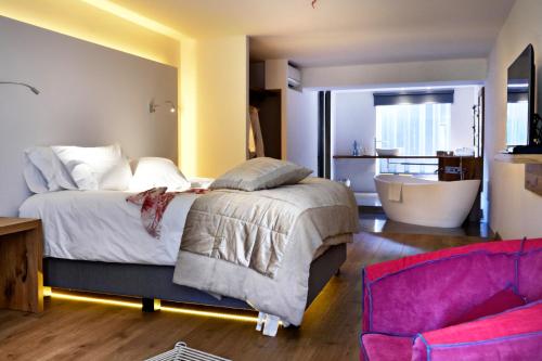 a bedroom with a bed and a bathroom with a tub at Boutique hotel Urbisol in Calders