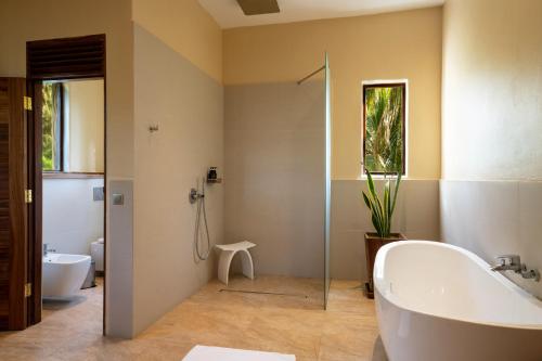 a bathroom with a tub and a sink and a toilet at Zanzibar White Sand Luxury Villas & Spa - Relais & Chateaux in Paje