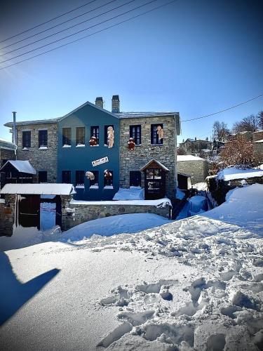 a blue building with snow in front of it at Rock Dandy La Maison de l'Ours - Nymfaio in Nimfaíon