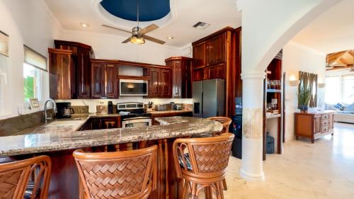 a kitchen with wooden cabinets and a island with bar stools at Belizean Cove Estates Beachfront Villas in San Pedro