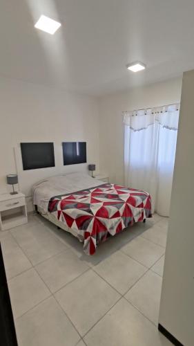 a bedroom with a bed with a red and white blanket at Departamentos Amalia in Ciudad Lujan de Cuyo