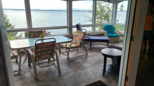 a room with chairs and a table and a view of the water at Loza house adirondack screened-in porch unit lake front in Plattsburgh
