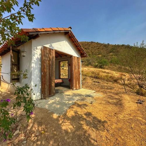 a small white building with a door in a field at Hospedagem Morro dos Muricis in Piumhi