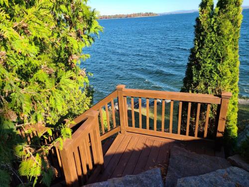 a wooden bench sitting next to a body of water at Loza house coastal design unit with lake & mountain views in Plattsburgh