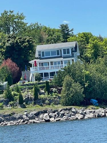 a large house on the shore of a body of water at Loza house coastal design unit with lake & mountain views in Plattsburgh