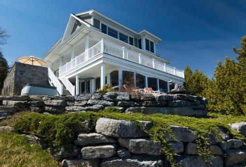 a large white house on top of a stone wall at Loza house coastal design unit with lake & mountain views in Plattsburgh