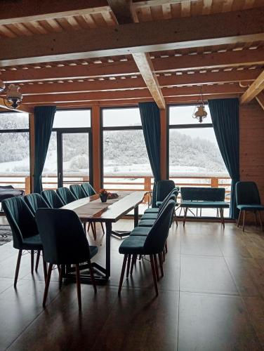 a dining room with a table and chairs and windows at Cabana 3 Stejari Maramureș in Călineşti