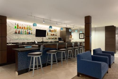 a bar with bar stools and a tv in a room at Wingate Slidell New Orleans in Slidell