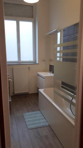 La salle de bains est pourvue d'une baignoire, d'un lavabo et de 2 fenêtres. dans l'établissement Grand appartement 2 chambres Calais centre ville, à Calais