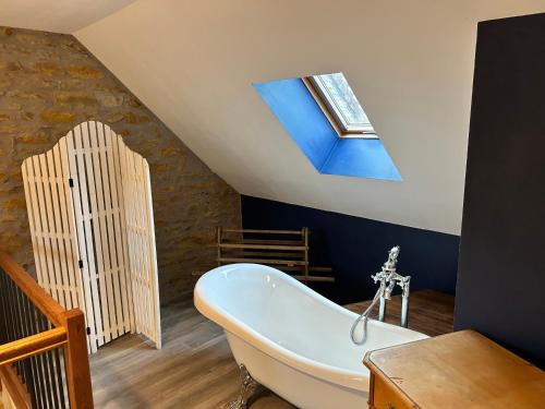a bathroom with a bath tub and a skylight at Le D'Tour Gourmand in Toulouse-le-Château