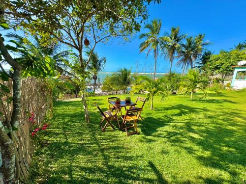 a table and chairs in a yard with palm trees at Casa Praia Beira Mar "PISO SUPERIOR" Guriú,Ce in Camocim