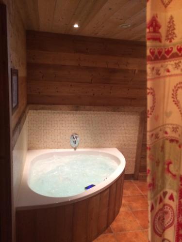 une baignoire dans une pièce avec un mur en bois dans l'établissement Chalet Au Bon Vieux Temps, au Grand-Bornand