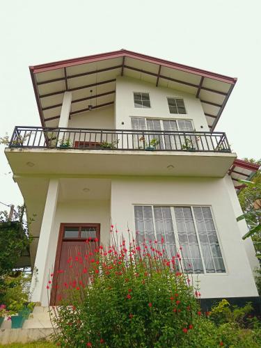 カルタラにあるSummer Dropの赤い花のバルコニー付きの建物