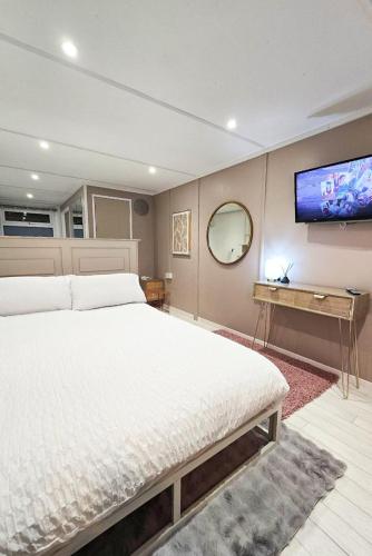 a bedroom with a large bed and a flat screen tv at The Fourwinds Cosy Cabin- 15mins to Belfast city in Belfast