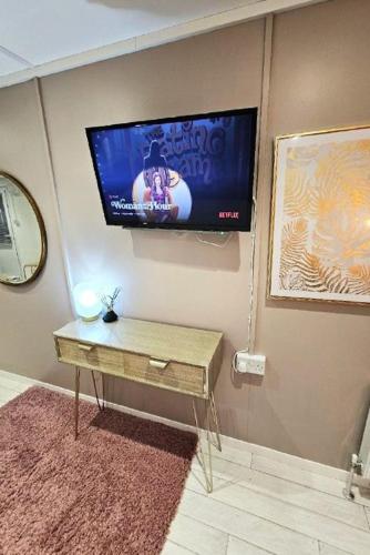 a flat screen tv on a wall with a table at The Fourwinds Cosy Cabin- 15mins to Belfast city in Belfast