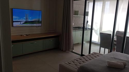 a hotel room with a tv and a bedroom with a bed at Studio 709 in Marília