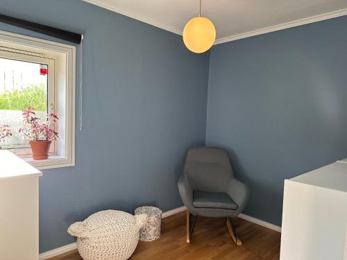 une pièce bleue avec une chaise et une fenêtre dans l'établissement Granåsen ski-VM, à Trondheim