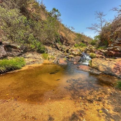 a stream of water in a rocky area with a waterfall at Hospedagem Morro dos Muricis in Piumhi