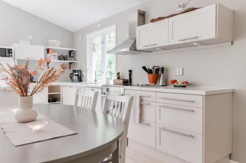 a white kitchen with a table and white cabinets at Green Villa in Tjörnarp