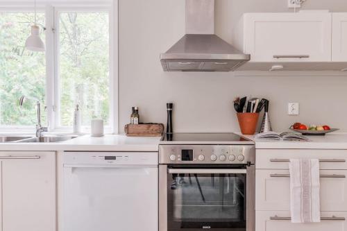 a white kitchen with a stove and a sink at Green Villa in Tjörnarp