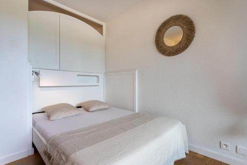 a white bedroom with a bed and a mirror at La Cigale Varoise - Hyères La Plage in Hyères