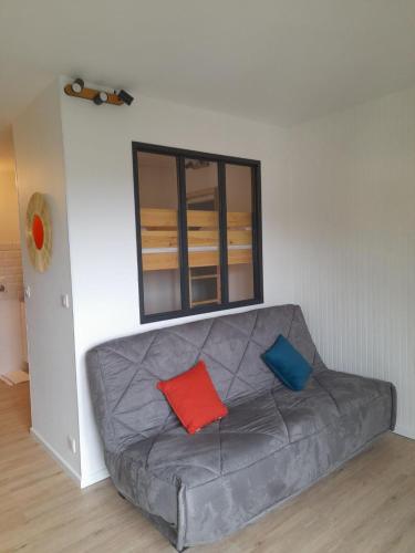 - un canapé gris avec 2 oreillers colorés dans l'établissement Le Lioran, à Le Lioran