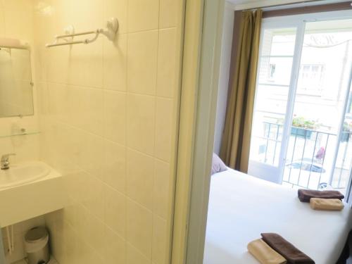 a bathroom with a bed and a sink and a window at Hotel de la Paix in Caen