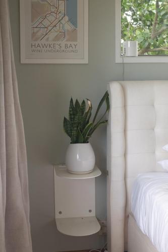 a plant in a white vase on a nightstand next to a bed at Evendale House in Hastings