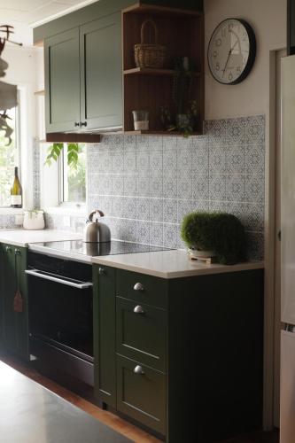 a kitchen with green cabinets and a clock on the wall at Evendale House in Hastings
