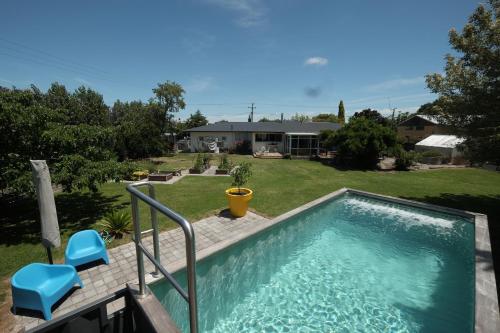 a swimming pool with two blue chairs and a house at Evendale House in Hastings