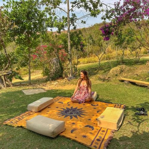 a girl sitting on a blanket on the grass at Hospedagem Morro dos Muricis in Piumhi