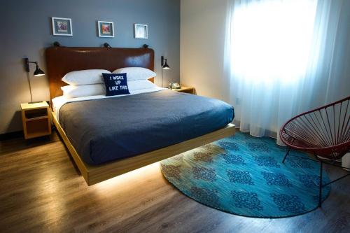 a bedroom with a bed with a blue blanket and a window at MOXY New Orleans Downtown/French Quarter Area in New Orleans