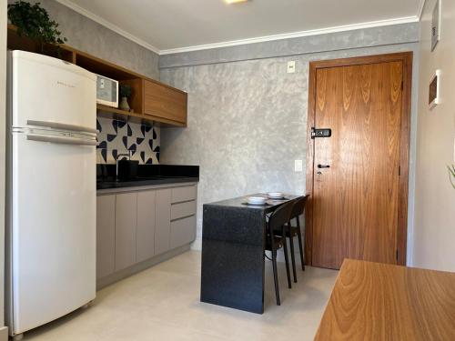 ブラジリアにあるFlat Fabuloso no Sudoesteのキッチン(白い冷蔵庫、黒いカウンタートップ付)