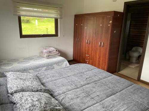 a bedroom with two beds and a dresser and a window at Casa Sra Oti, Tipo Hostal con vista al mar Puerto Montt - CHINQUIHUE in Puerto Montt