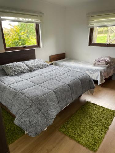 two beds in a bedroom with two windows at Casa Sra Oti, Tipo Hostal con vista al mar Puerto Montt - CHINQUIHUE in Puerto Montt