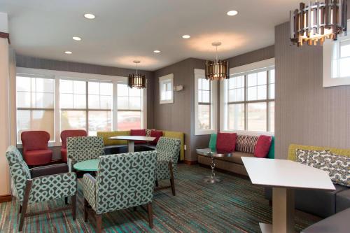 a waiting room with tables and chairs and windows at Residence Inn Moline Quad Cities in Moline