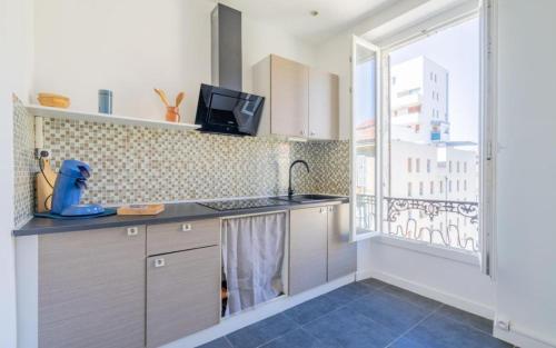 une cuisine avec un évier et une grande fenêtre dans l'établissement Joli T2 quartier de la Joliette 2 min du tramway, à Marseille