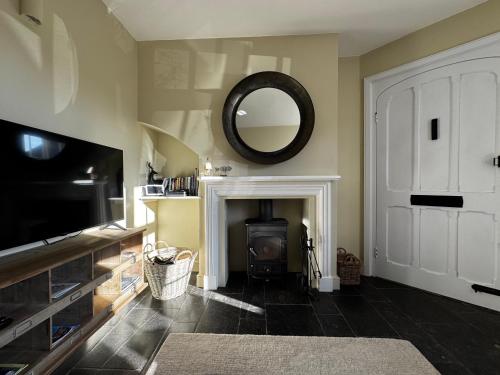 a living room with a fireplace and a mirror at Cosy 2 bed cottage in beautiful Orford in Orford