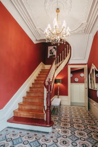 a staircase with red walls and a chandelier at Vintage Beach House in Matosinhos
