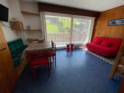 un salon avec une table et un canapé rouge dans l'établissement Studio au pied des pistes à Morzine, à Morzine